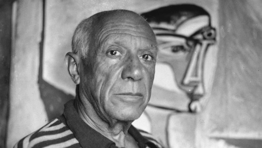 Pablo Picasso in front of one of his paintings.