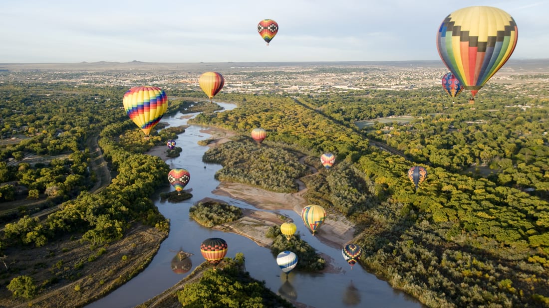 Hot air balloons drifting over the Rio Grande River in Albuquerque, New Mexico.