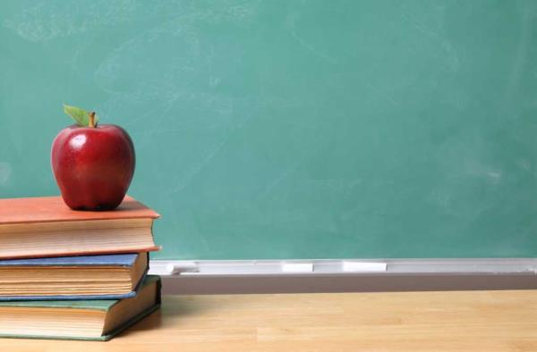 shutterstock 17894746 red apple on stack of books on wood desk in front of green chalkboard