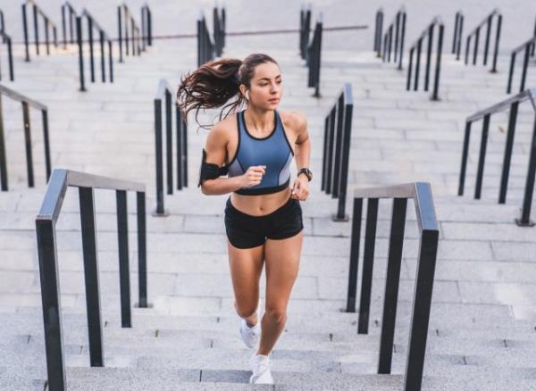 woman running up steps, co<em></em>ncept of tips to avoid belly fat