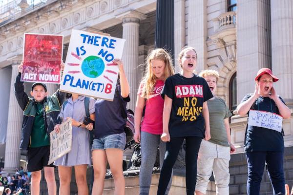 Children at a school strike for climate shout and hold signs.