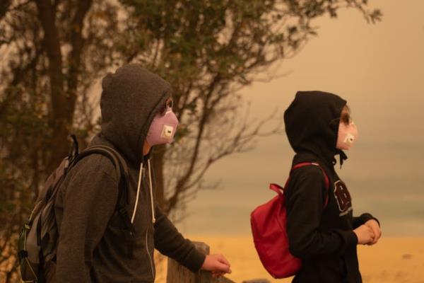 A man and teenage daughter wear particle masks and sunglasses in a smoke-filled landscape.