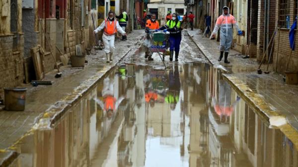 Agents wearing protective jumpsuits take part in cleaning works in a street covered in mud in Paiporta, south of Valencia, eastern Spain, on 13 November 2024.