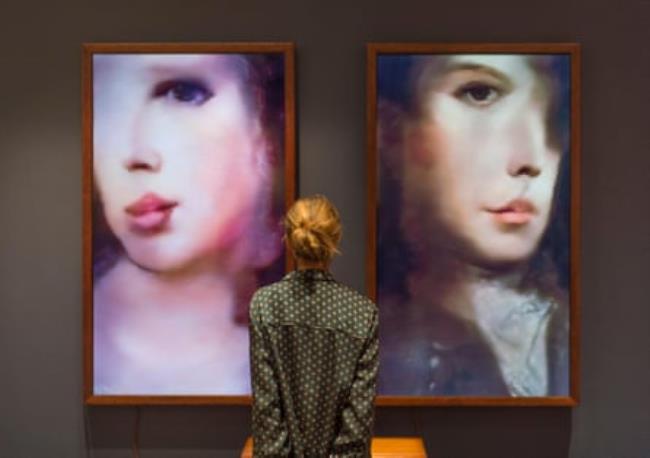 Woman standing in front of two AI generated artworks hung in f<em></em>rames